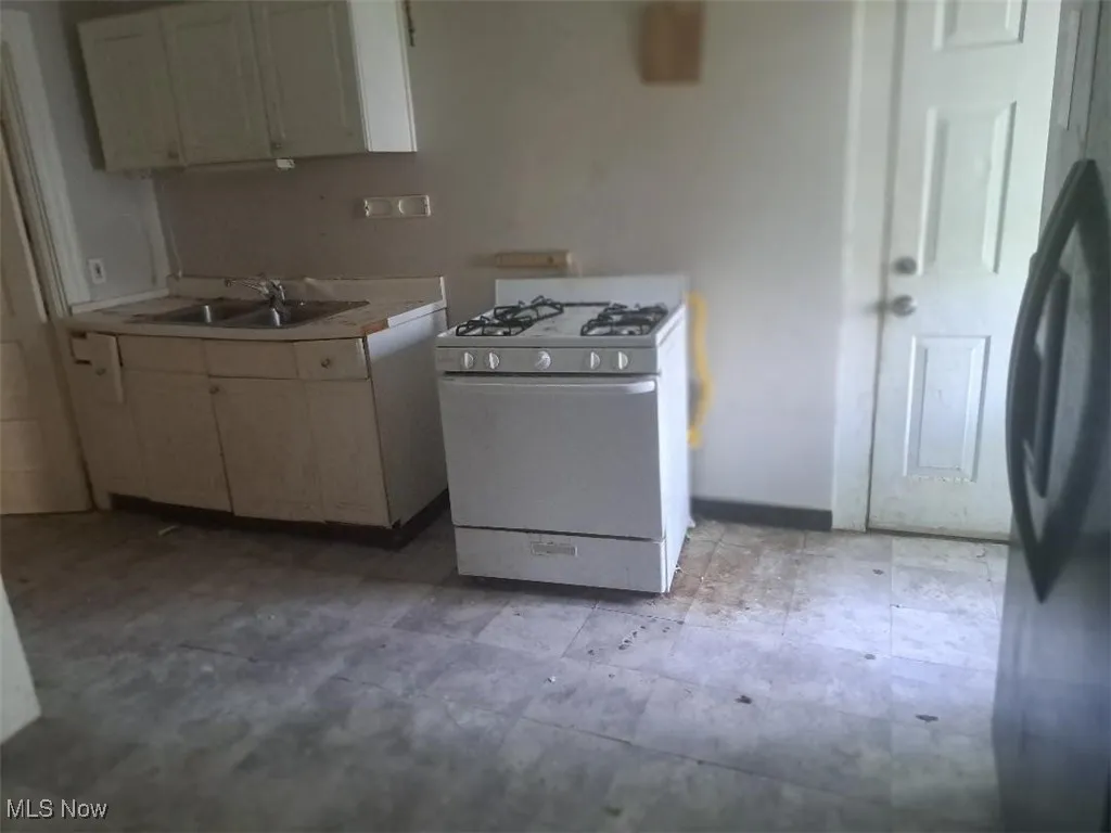 Kitchen featuring white gas stove, freestanding refrigerator, and light countertops