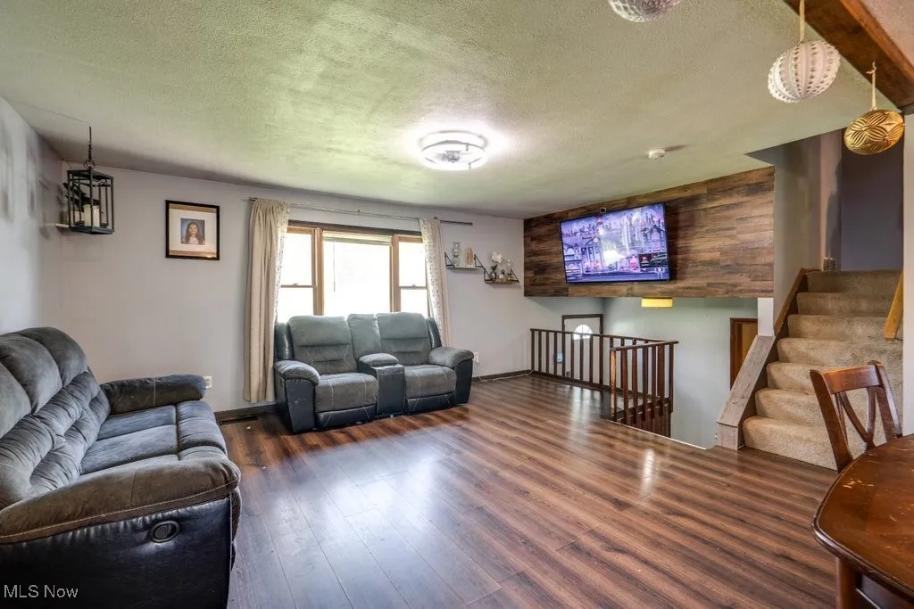 Living area featuring a textured ceiling, wood finished floors, and stairs