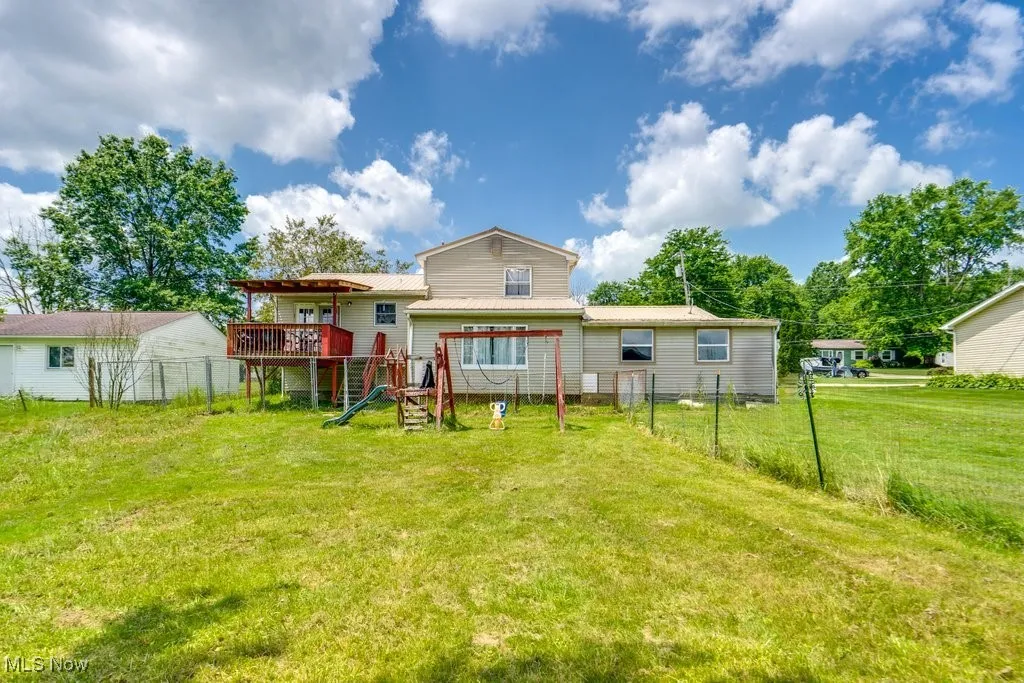 Back of house with a wooden deck and a metal roof