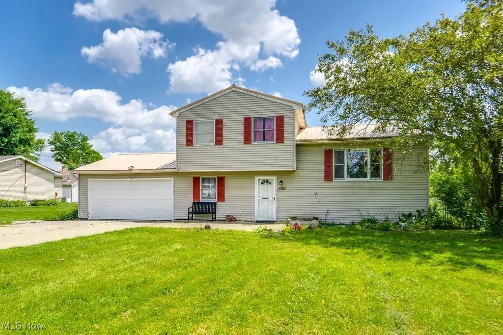 Tri-level home featuring a metal roof, an attached garage, a front lawn, and driveway