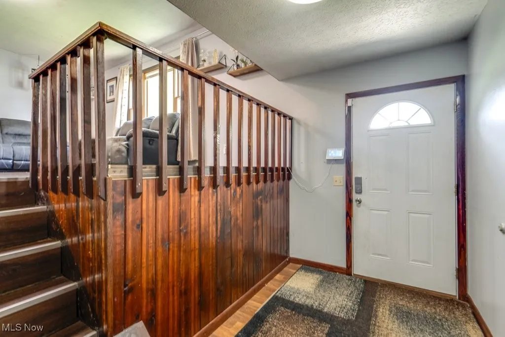 Foyer entrance featuring stairway and a textured ceiling