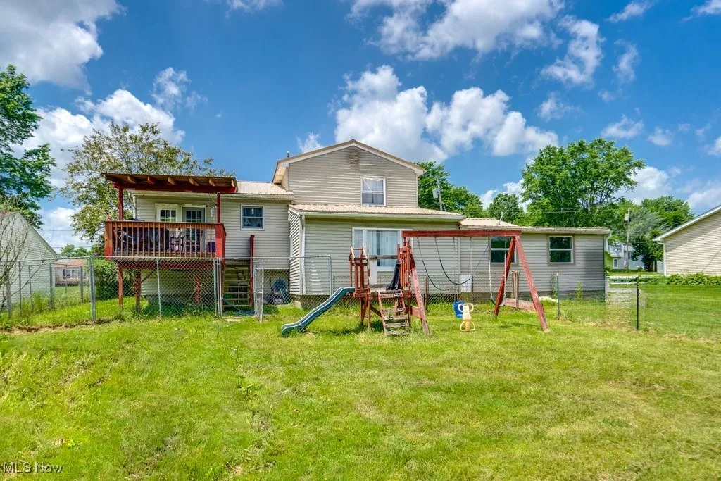 Rear view of house with a playground and a wooden deck