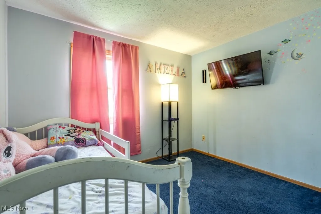 Carpeted bedroom with a textured ceiling and baseboards