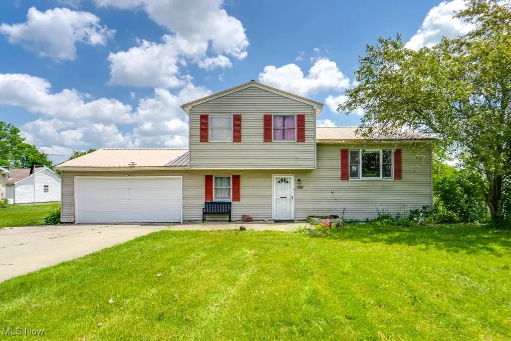 Tri-level home with a metal roof, a front lawn, an attached garage, and concrete driveway