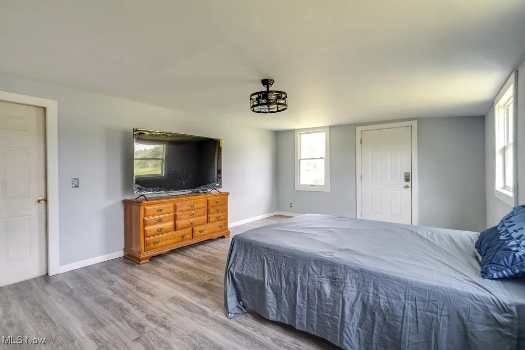 Bedroom with wood finished floors and multiple windows