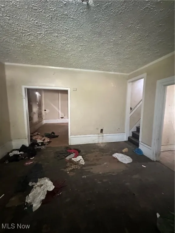 Unfurnished living room with a textured ceiling and stairway