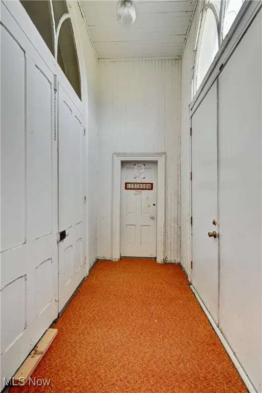 Hallway with light colored carpet and wooden walls