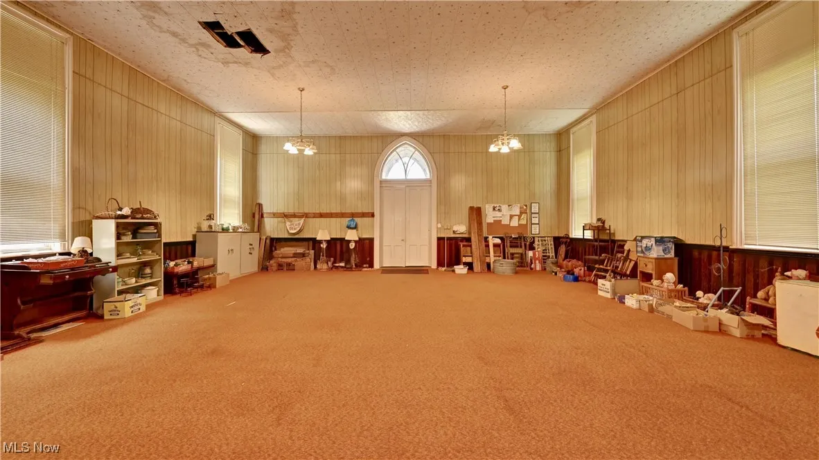 Misc room with a chandelier, carpet floors, and wood walls