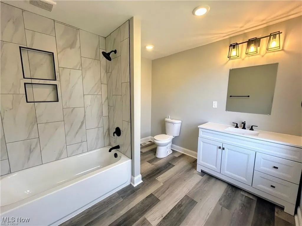 Bathroom featuring vanity, shower / tub combination, wood finished floors, and recessed lighting