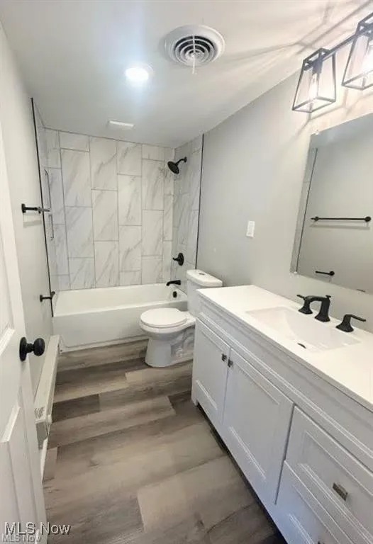 Full bath featuring vanity,  shower combination, and wood finished floors