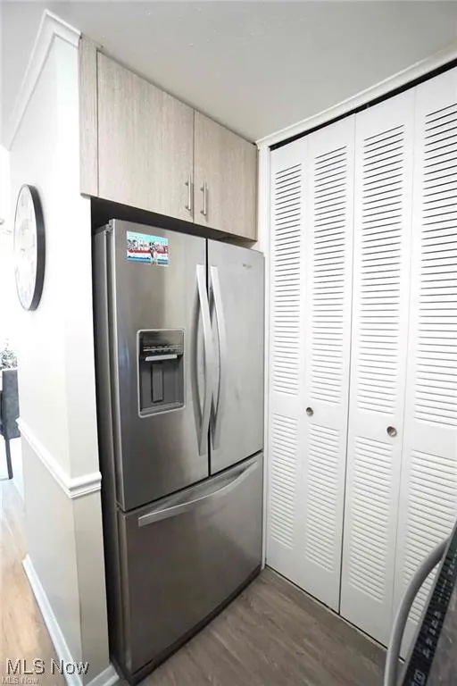 Kitchen with stainless steel refrigerator with ice dispenser, wood finished floors, and light brown cabinetry