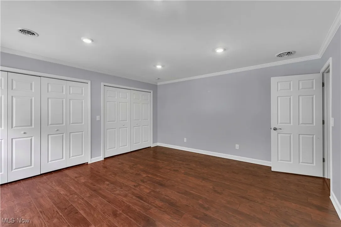 2nd floor bedroom featuring crown molding, two closets, wood-type flooring, and recessed lighting