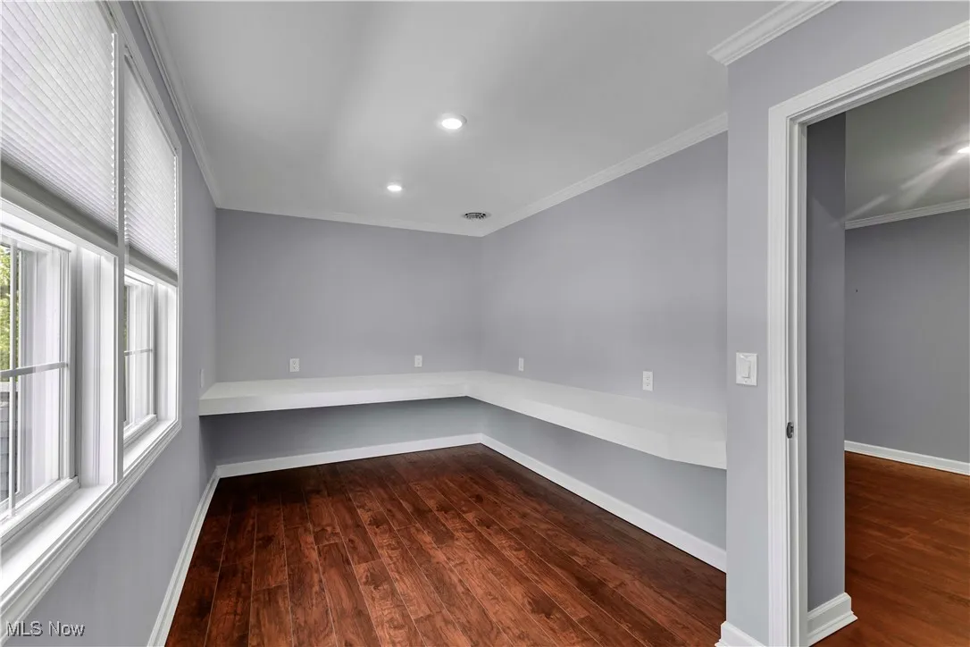 Office space featuring built in desk, two windows, recessed lighting and wood style floors.