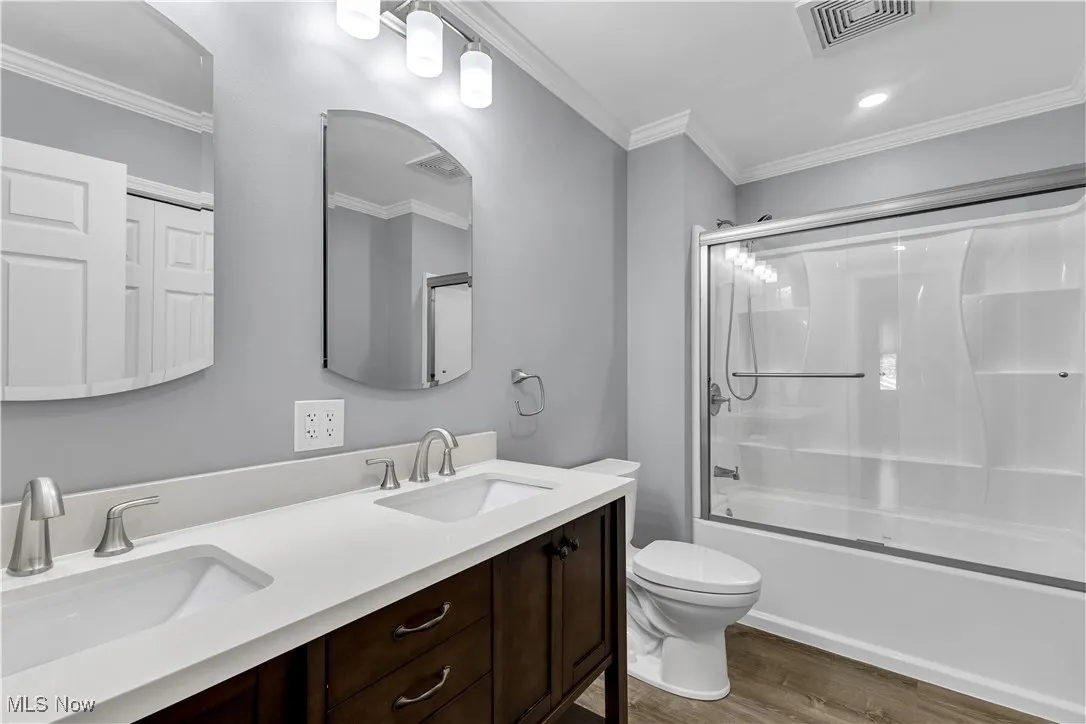 Full bathroom on 2nd floor with dual vanities, tub/shower combo, modern light fixtures and vinyl plank flooring.