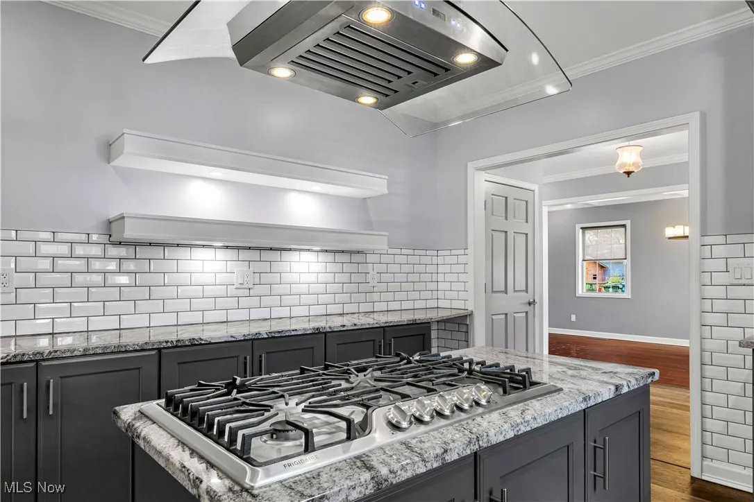 Kitchen featuring floating island range hood, floating shelving with custom lighting