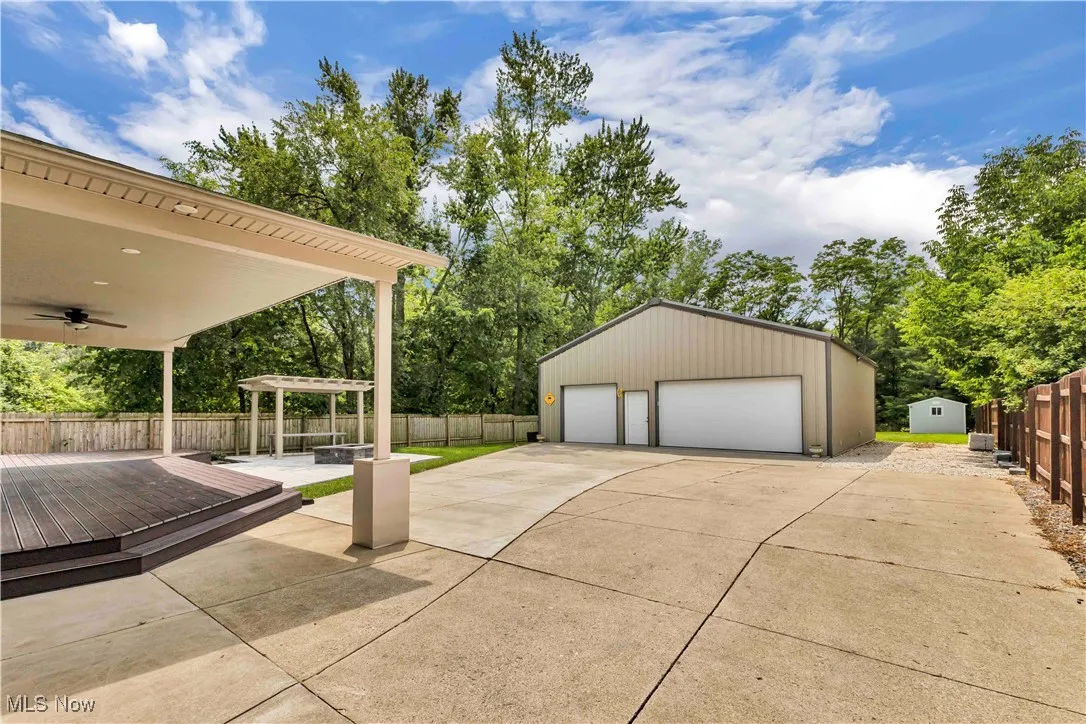 View of the expansive covered back composite deck with ceiling fan and large outbuilding