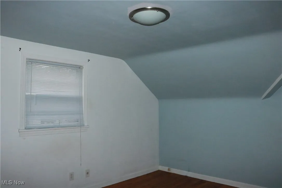Additional living space featuring vaulted ceiling and dark wood finished floors