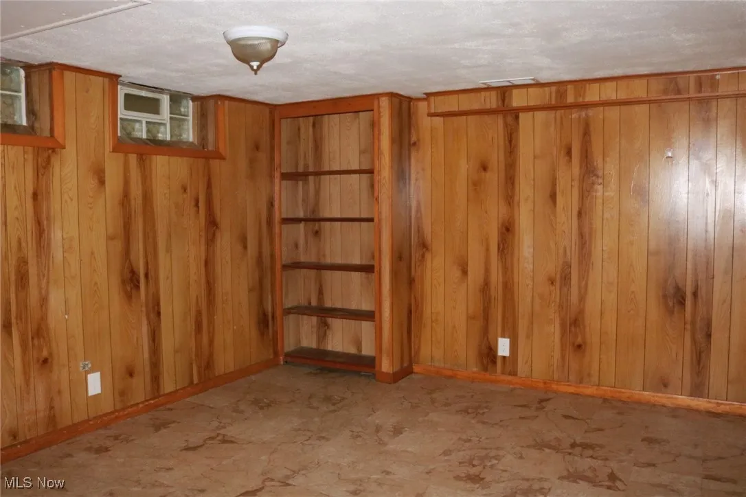 Empty room featuring wood walls and baseboards