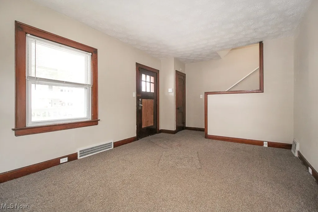 Unfurnished room featuring light carpet and a textured ceiling