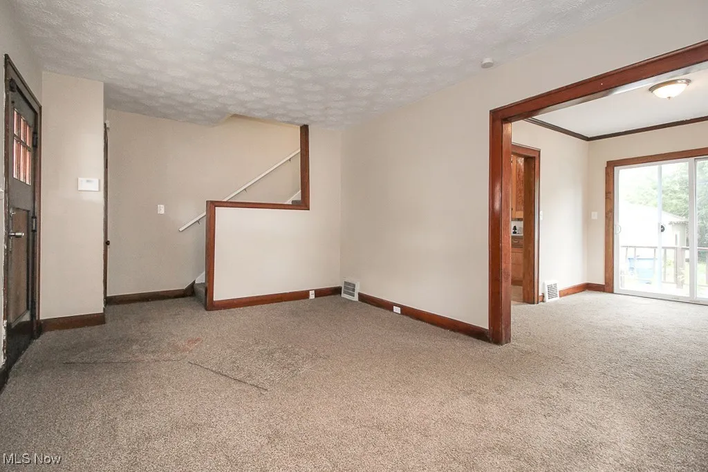 Spare room featuring carpet flooring, stairs, and a textured ceiling