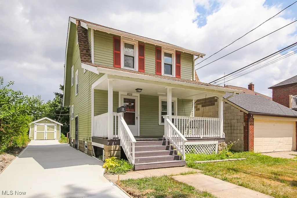 View of front of house featuring covered porch, a storage unit, and an attached garage