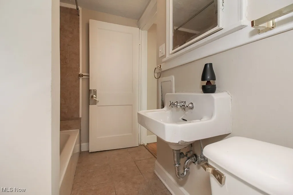 Full bathroom with tile patterned floors and a tub to relax in