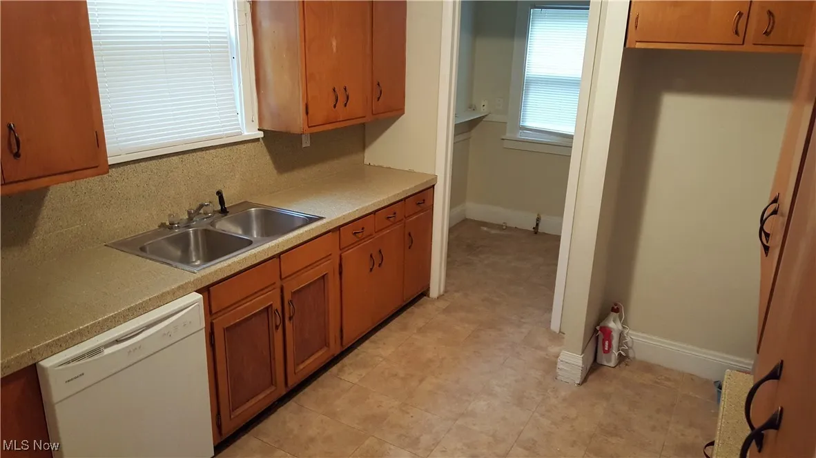 Kitchen with dishwasher, brown cabinetry, and light countertops