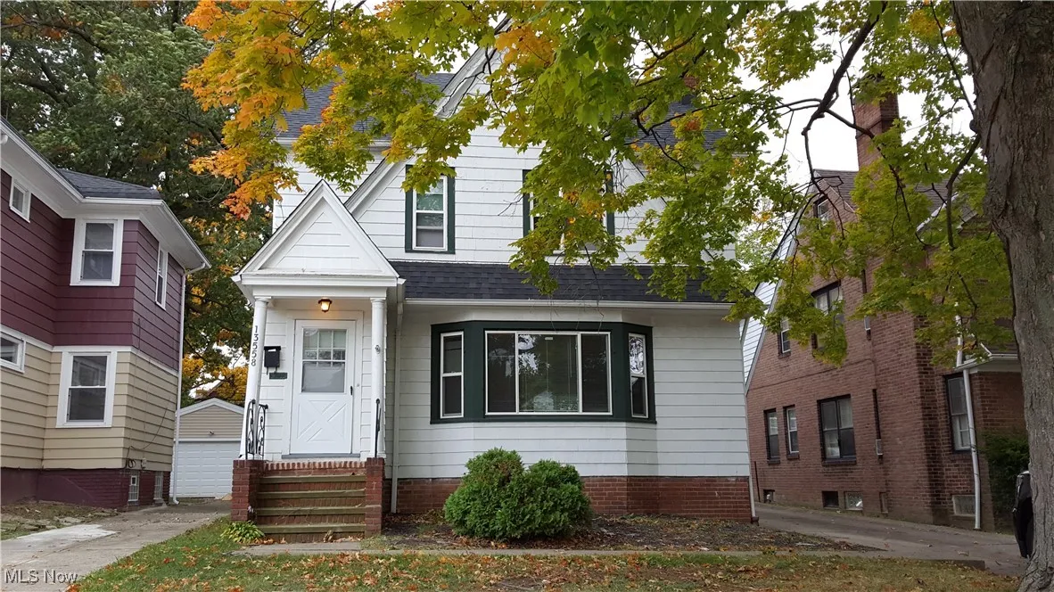 View of front of property with roof with shingles, entry steps, an outbuilding, and a detached garage