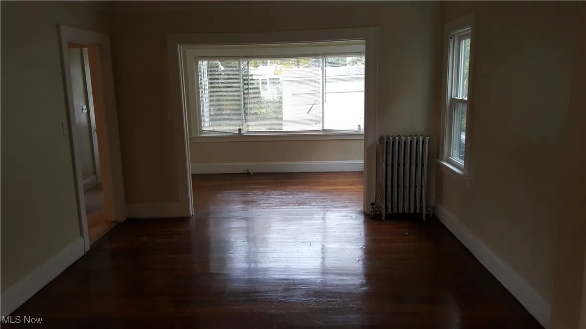 Unfurnished room with radiator and dark wood-style floors