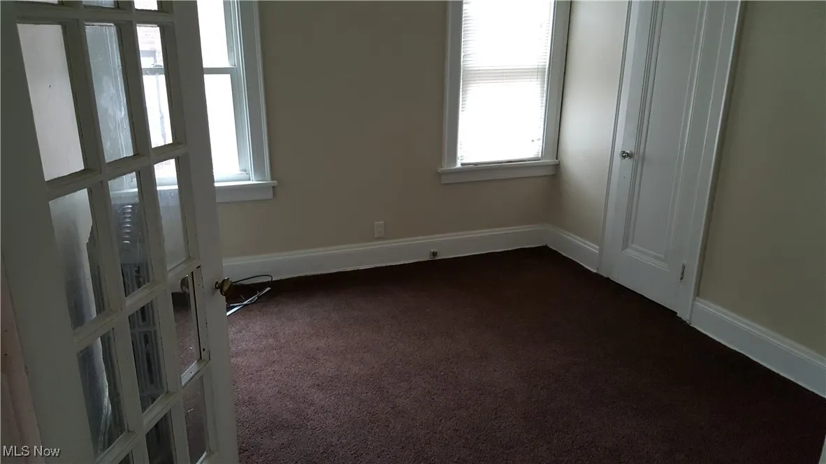Empty room featuring dark colored carpet and baseboards