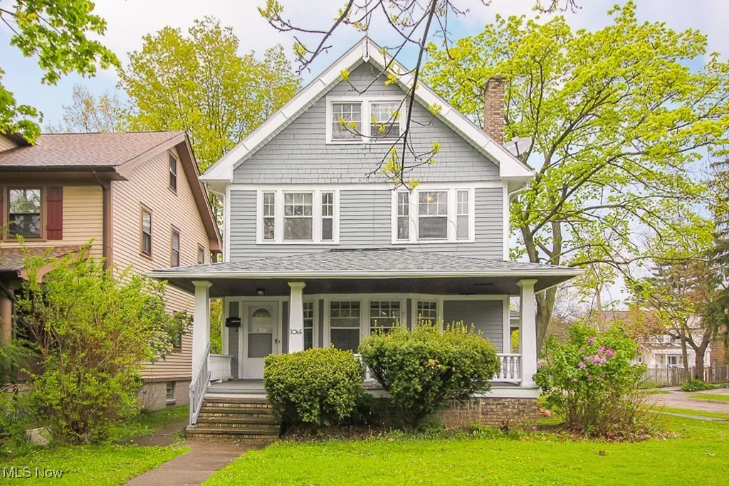 American foursquare style home with covered porch, a chimney, and a front yard