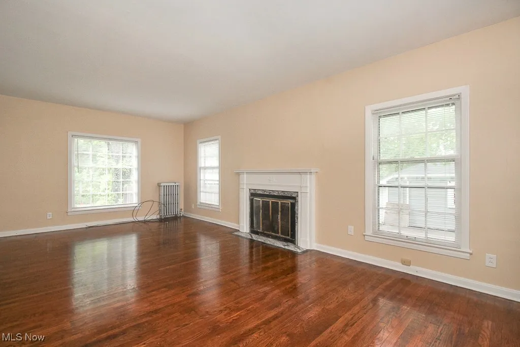 Unfurnished living room with radiator, wood finished floors, and a premium fireplace