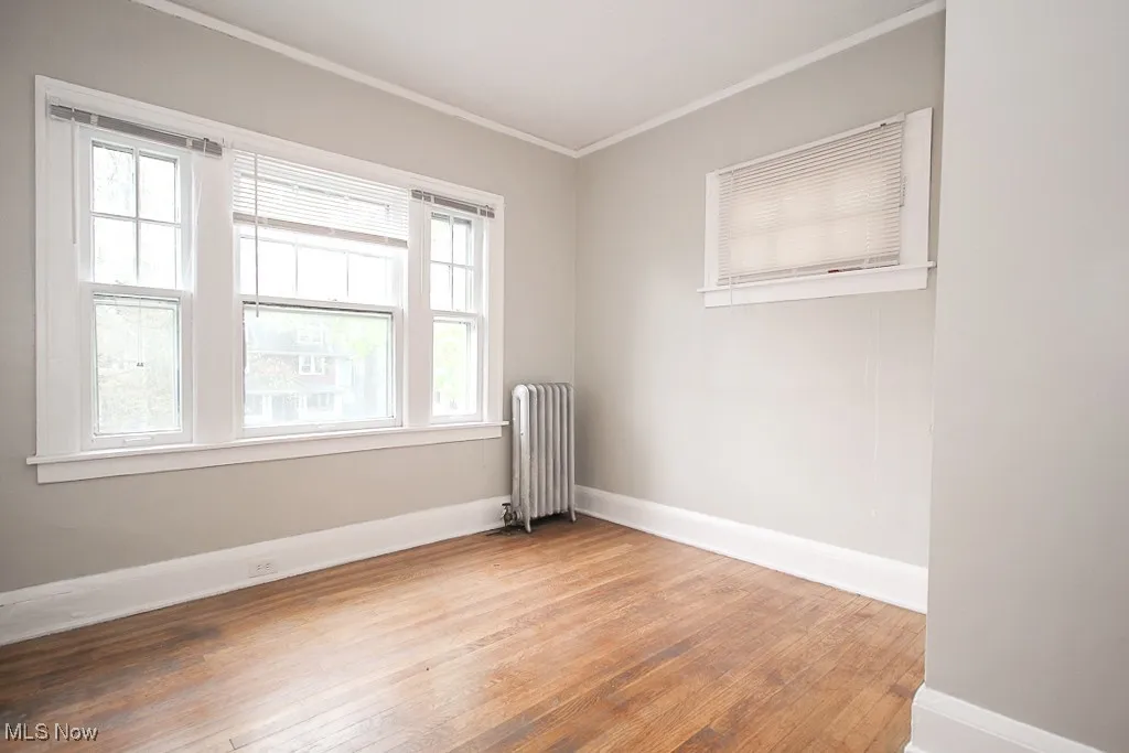 Spare room with radiator, ornamental molding, and hardwood / wood-style flooring