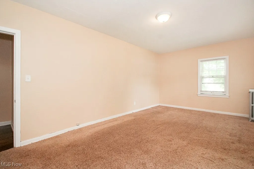 Spare room featuring carpet flooring and baseboards