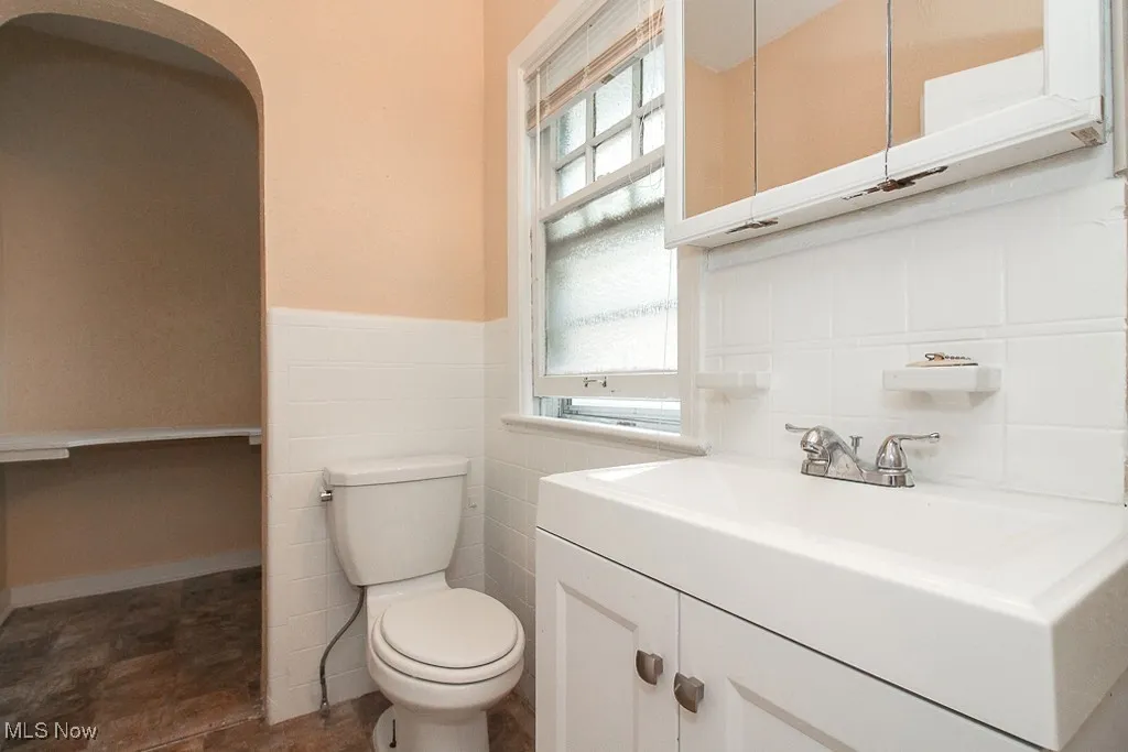 Half bathroom with vanity, plenty of natural light, and wainscoting