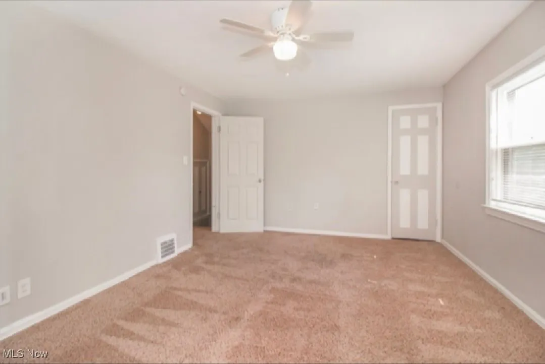 Carpeted spare room with a ceiling fan and baseboards