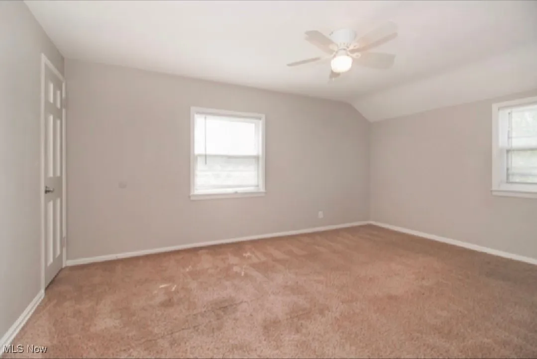 Empty room with carpet floors, lofted ceiling, and ceiling fan