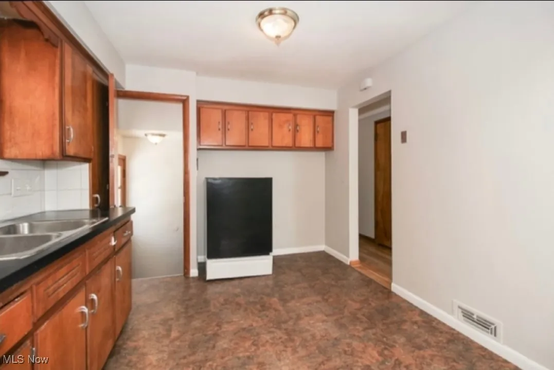 Kitchen featuring brown cabinetry, backsplash, and dark countertops