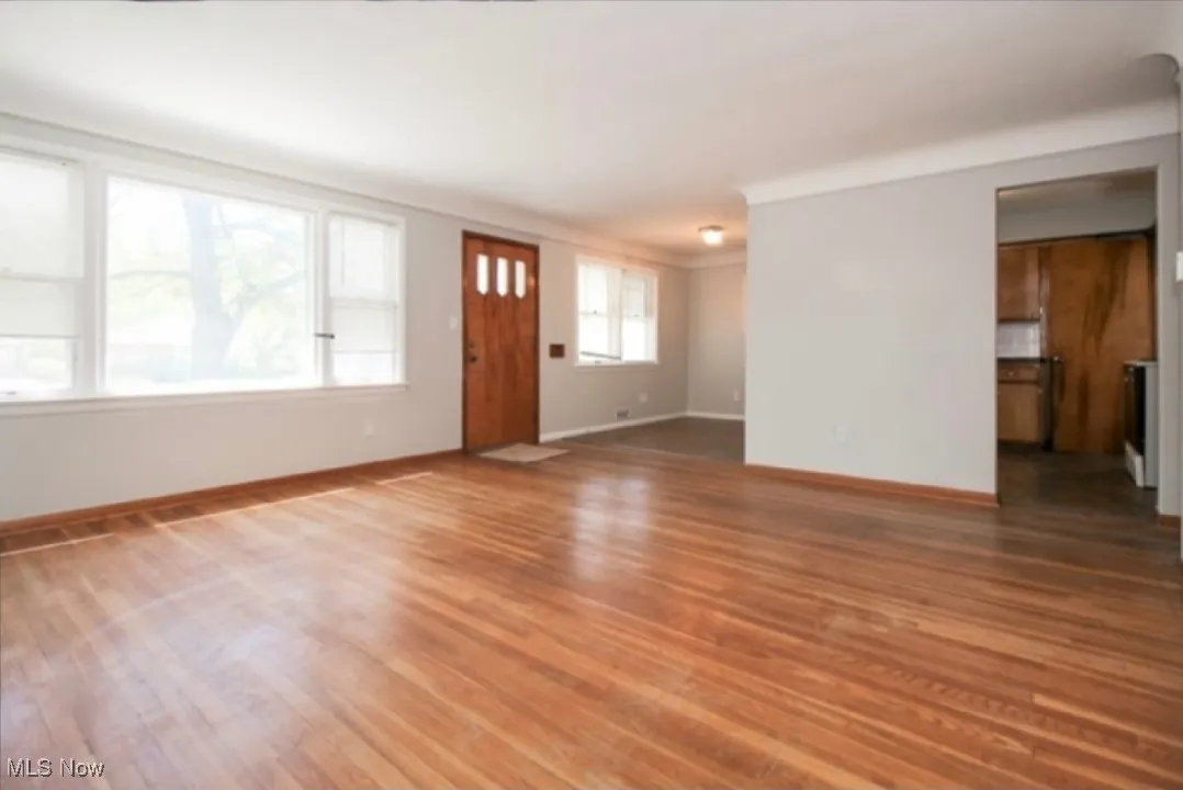 Unfurnished living room with wood finished floors and baseboards