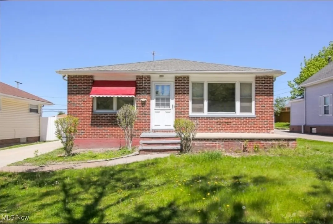 Bungalow featuring brick siding and a front yard