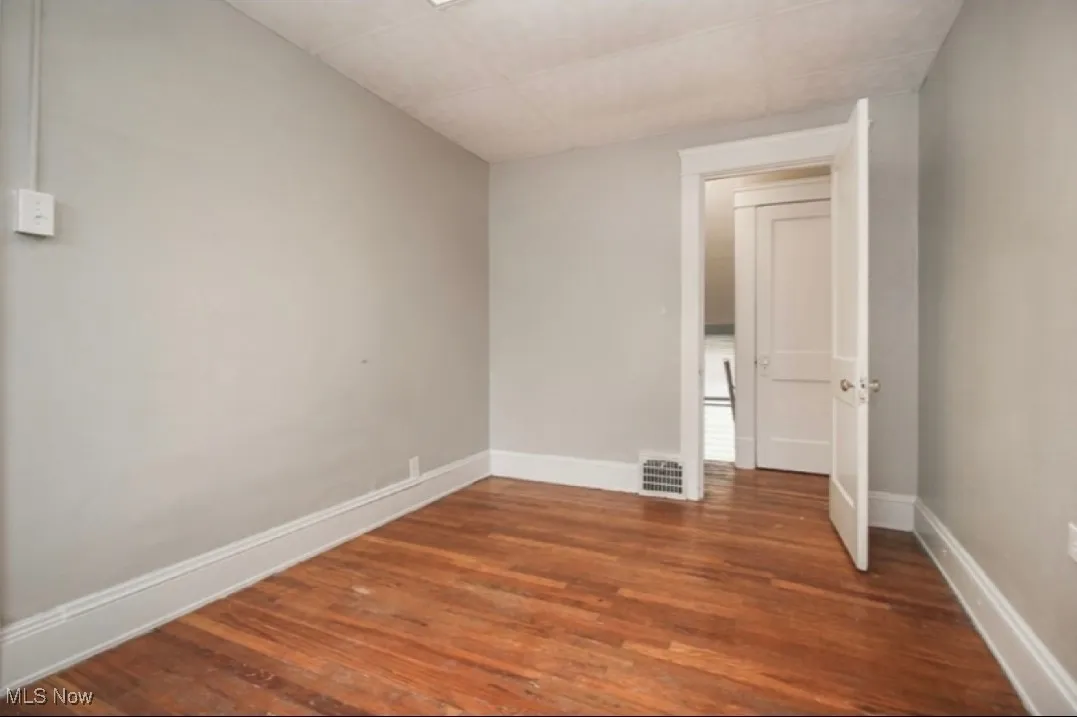 Empty room with wood finished floors and a paneled ceiling