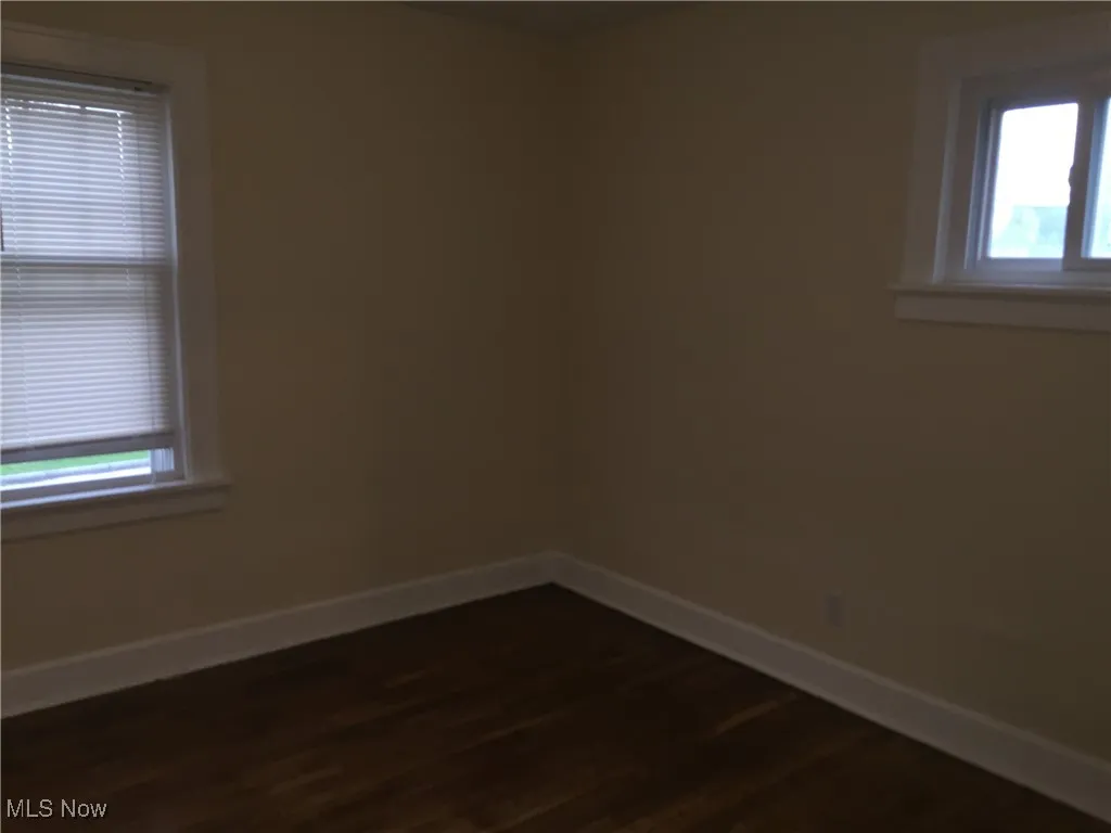 Empty room with baseboards and dark wood-style flooring