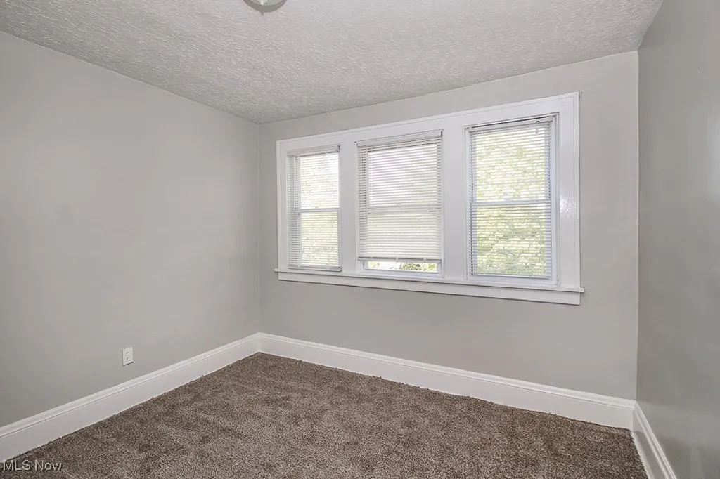 Spare room with plenty of natural light, dark colored carpet, and a textured ceiling