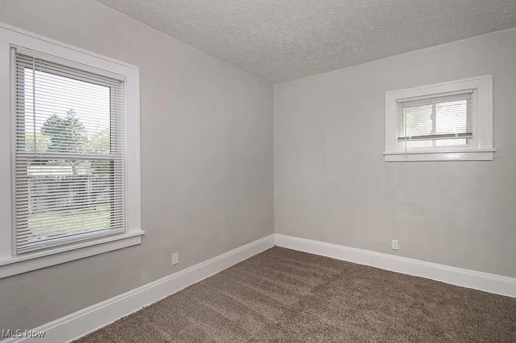 Spare room with dark colored carpet and a textured ceiling