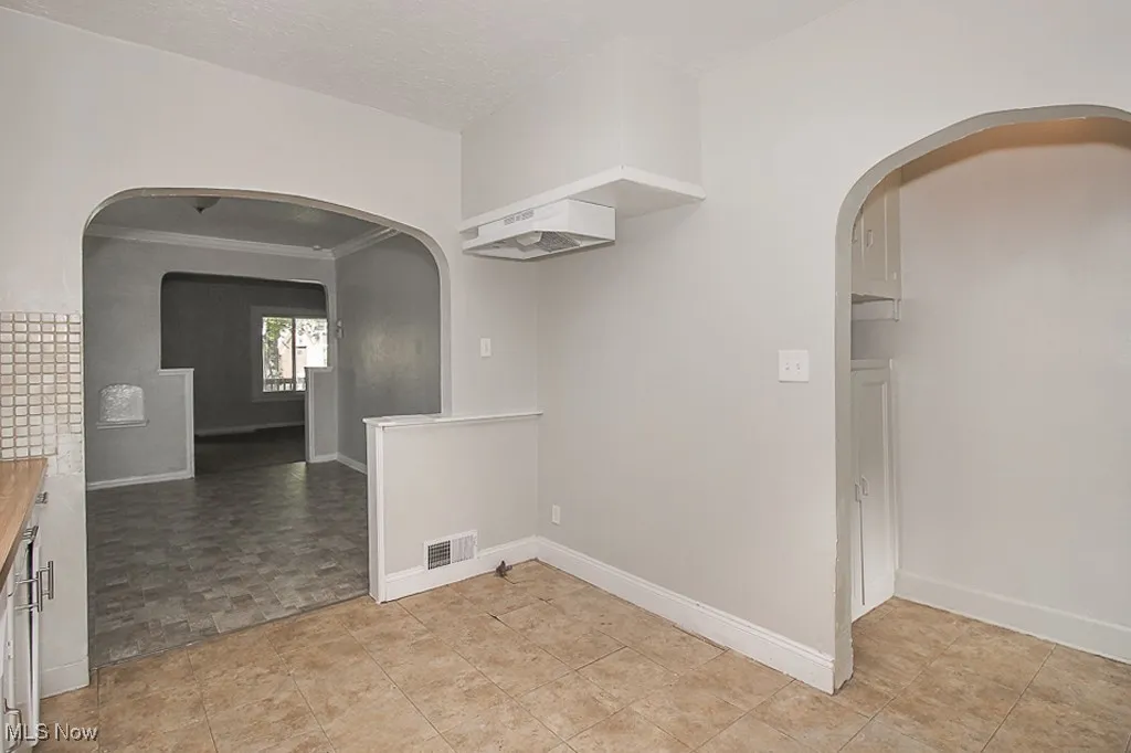 Spare room featuring ornamental molding and arched walkways