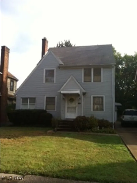 View of front facade with a front yard and a chimney
