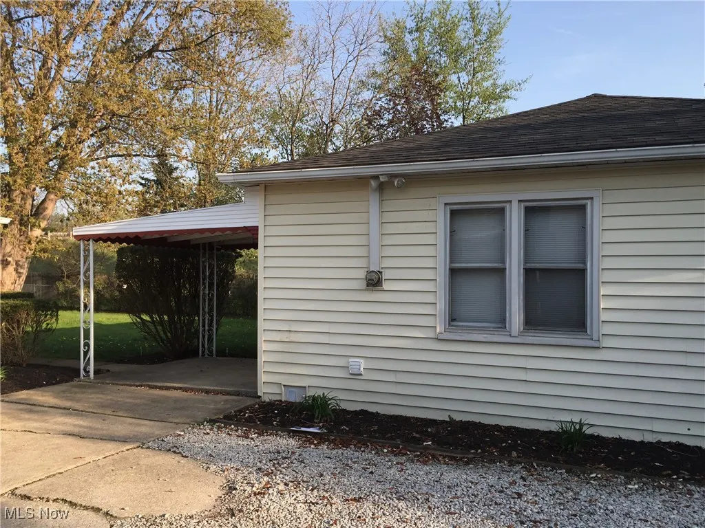 View of property exterior featuring a shingled roof and concrete driveway
