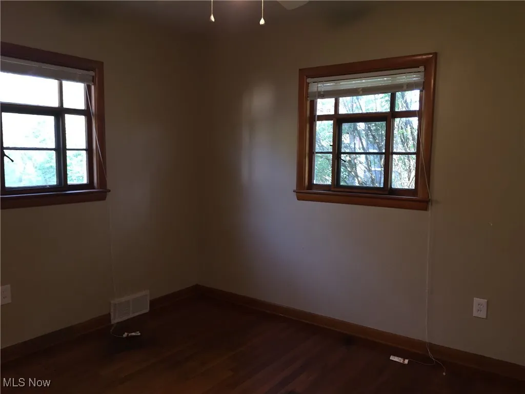 Empty room featuring dark wood-style flooring and baseboards