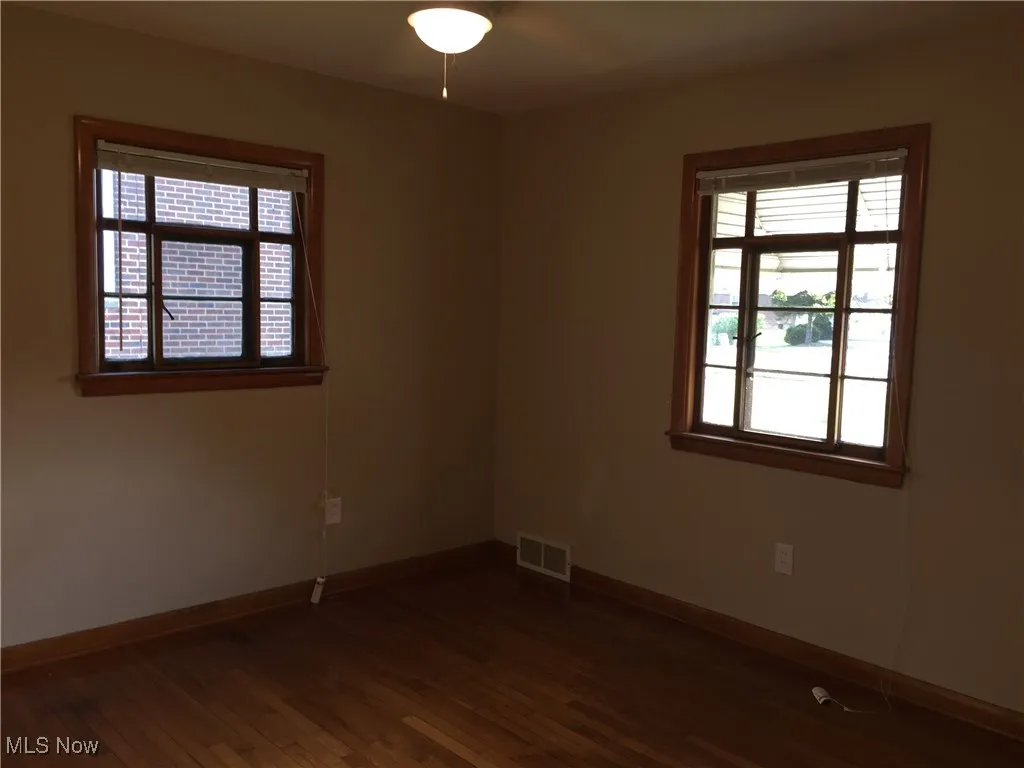 Unfurnished room with dark wood-type flooring and healthy amount of natural light