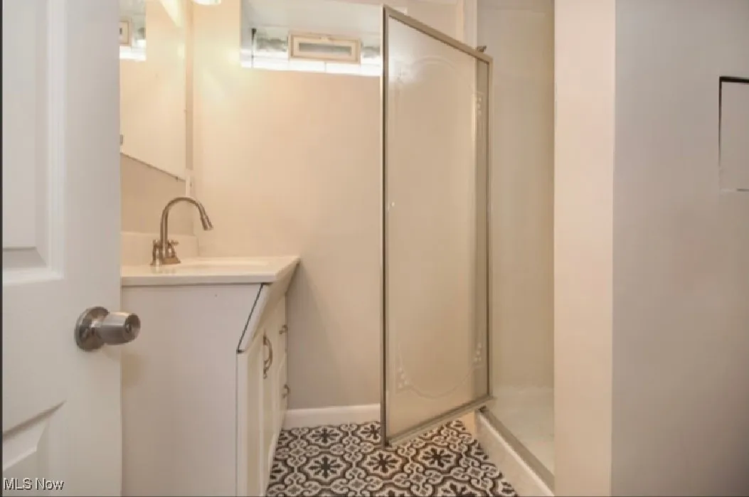 Full bath featuring vanity, a stall shower, and tile patterned flooring